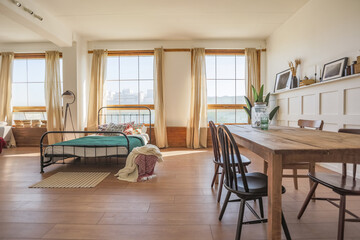 Vintage studio apartment interior in light colors in old style. huge room with large windows with a living room area and a bedroom area. direct sunlight inside.