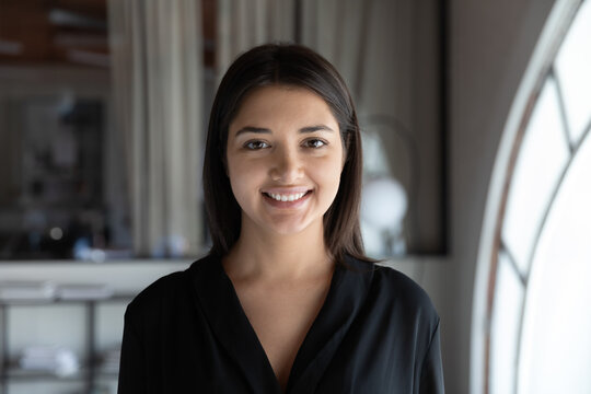Profile picture of smiling indian young businesswoman look at camera posing at workplace, headshot portrait of happy millennial ethnic female employee show confidence, optimism, employment concept