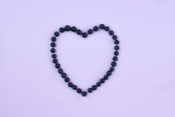 Blueberries on a lilac background, laid out in the shape of a heart