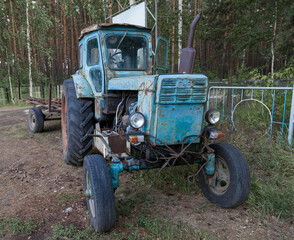 Old rusty Belarusian tractor stot at the entrance to the village of Ordynskoye as a monument to agriculture. Scrap metal recycling.