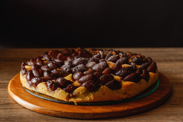 Traditional homemade plum tart with powdered sugar on a wooden plate placen on wooden kitchen table
