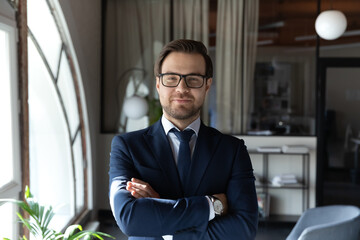 Profile picture of confident young caucasian businessman in formal suit and glasses posing in...