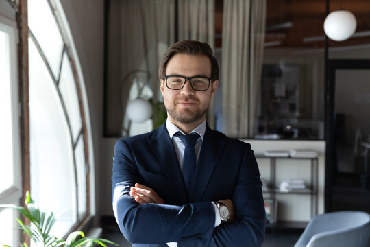 Profile picture of confident young caucasian businessman in formal suit and glasses posing in office, portrait of successful male boss or director show confidence and leadership, recruitment concept