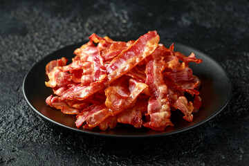 Fried crunchy Streaky Bacon pieces in a black plate