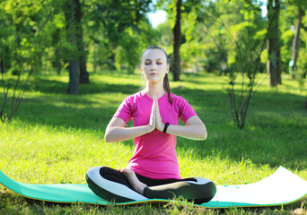 Beautiful young blonde sitting in lotus position meditating in the park Active lifestyle