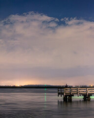 Comet Neowise, setting over a fishing pier and dramatic storm clouds after sunset. Long Island New York