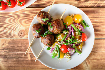 Lula kebab from lamb on a wooden skewer with a salad from Cherry tomatoes, red onions and green beans. A white plate on an old wooden background. Selective focus.