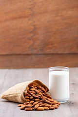 Close Up glass of Almond milk in a glass with Almond seeds. an wooden background