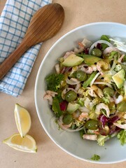Salad with shrimp, avocado, lemon and arugula. On a wooden table with a tea towel and a wooden spoon