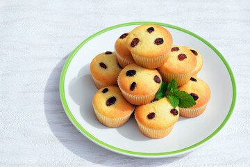Freshly baked homemade muffins - vanilla muffins with raisins, decorated with melissa leaves