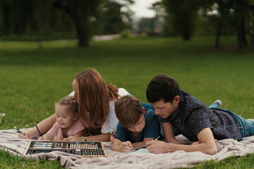 Happy young couple spending time with their daughter and son outdoors in the nature. Weekend activities concept