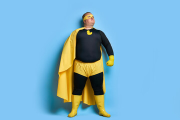 superhero fat caucasian male in mask and protective gloves posing. man looks as Mr.Proper, going to...