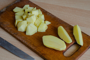 Serving of diced raw potatoes on wooden cutting board.