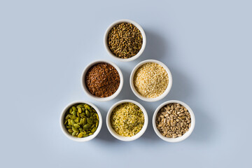 Different seeds - hemp, sesame, sunflowers seeds and pumpkin seeds in small bowl top view on blue background
