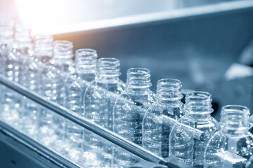 The PET bottles  on the conveyor belt for filling process in the drinking water factory. The hi-technology of plastic bottle manufacturing process.