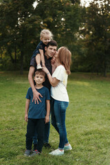 Happy young couple spending time with their daughter and son outdoors in the nature. Weekend activities concept