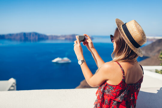 Santorini traveler woman taking photo of sea landscape on phone. Tourism, traveling, summer vacation