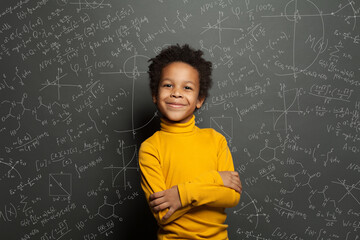 Smart African American child student boy on chalkboard background with science formulas