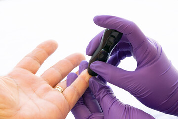 Close up of a healthcare assistant doing the glucose test to a diabetes patient on a white background.