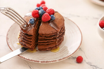 Eating of delicious chocolate pancakes on table
