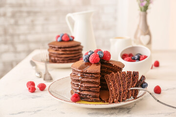 Eating of delicious chocolate pancakes on table