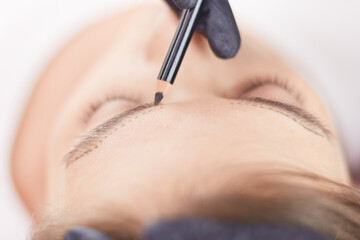Cosmetologist applying permanent make up on eyebrows