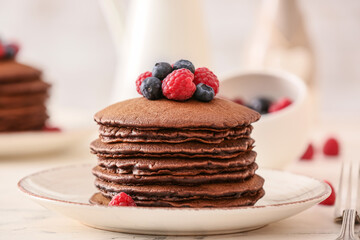 Plate with delicious chocolate pancakes and berries on table