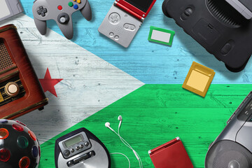 Djibouti retro gaming concept. A collection of retro video game controllers shot from above on a national background. © sezerozger