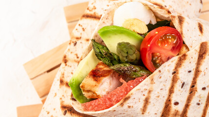Burritos wraps with asparagus, cherry tomatoes, avocado, chicken fillet on a light background, top view. burrito, mexican food. Food recipe background. Close up