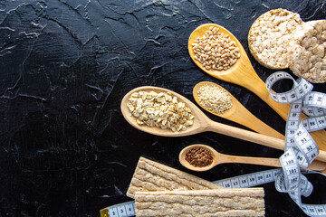 different types of diet bread, round buckwheat crispbread, wheat crispbread and crispbread with oatmeal flakes and wheat grains, flax and sesame seeds, healthy flour  - body measuring tape  background