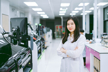 young smiling scientist in white lab coat standing with automation blood analyzer at medical laboratory