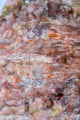 Background with the surface of a piece of red granite interspersed with quartz in soft focus under high magnification
