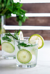 Cold  fresh summer cocktail with lime, mint,rosemary and ice in glasses on a light background