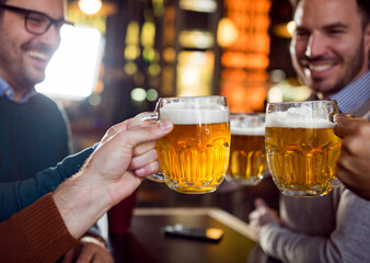 Friends clicking with glass of beer in pub