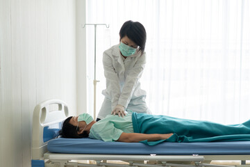 doctor wearing gloves doing cardiopulmonary resuscitation or cpr to help asian senior patient who...