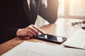 Businesswoman using calculator in mobile phone working in the office.