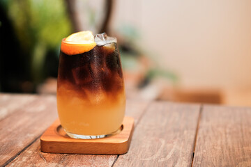 A glass of ice black coffee with paper straw in coffee cafe