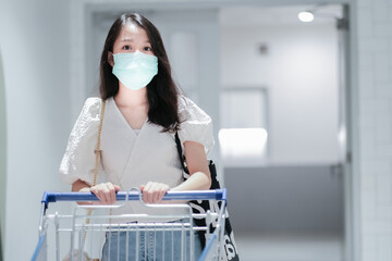 Asian girl in with shirt wear surgical mask to protect the Covid-19 in supermarket, New normal lifestyle.