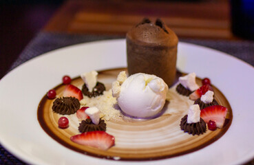 Delicious dessert with ice cream and cake and berry fruits. Chocolate brownie with vanilla ice cream, nuts and berry, served on white plate. Cake, Ice Cream, Chocolate.
