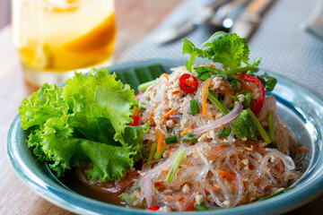 Selected focus, Spicy vermicelli salad on a table. Vermicelli spicy salad, with fresh vegetables and herbs. Spicy noodle salad, Spicy vermicelli salad (Yum Woon Sen). © Avirut S.