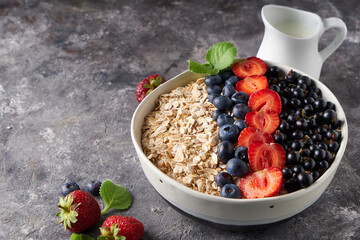 Healthy breakfast, muesli with currants, blueberries and strawberries in bawl on dark backgrund