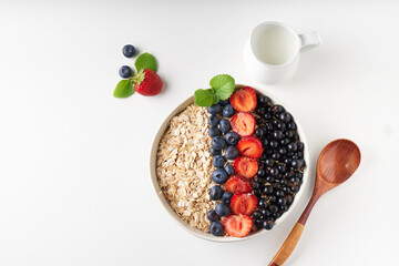Healthy breakfast, muesli with currants, blueberries and strawberries served in bawl on light...