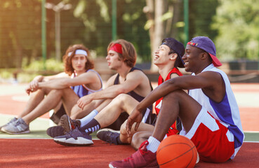 Team of professional basketballers communicating after tournament at outdoor arena, copy space