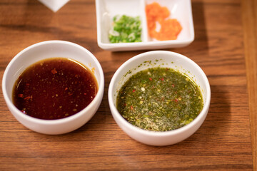 A bowl of spicy seafood (right) and ponzu soy (left) sauces, normally eating in Thai style BBQ grilled restaurant. Selective focus at seafood sauce surface part.