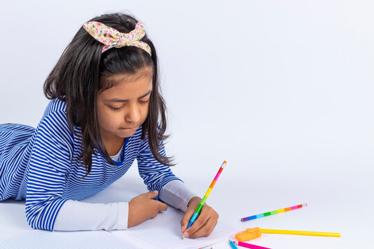 Cute left-handed girl is writing with a pencil in her notebook.