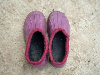 Lilac galoshes warmed on a concrete surface