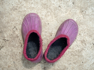 Lilac galoshes warmed on a concrete surface