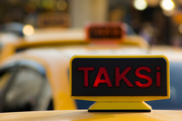 Three yellow taxis in a row, waiting for passengers, in Taksim square, Istanbul, Turkey. Focus on one taxi, the rest is blurry.