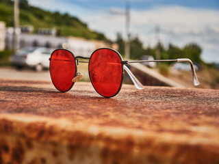 Old red sunglasses on a concrete surface. Scratched glass