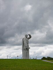gray statues of soldiers on a green hill in memory of those killed in the second world war on the territory of russia